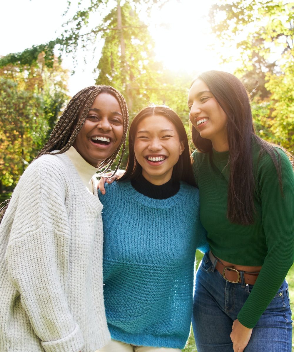 Vertical Portrait of three girls outside looking at camera. Friends multi-ethnic groups of people